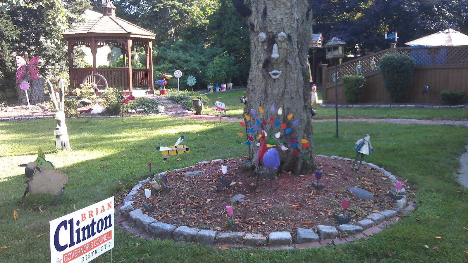 A tree with a face on it in the middle of a colorfully decorated garden