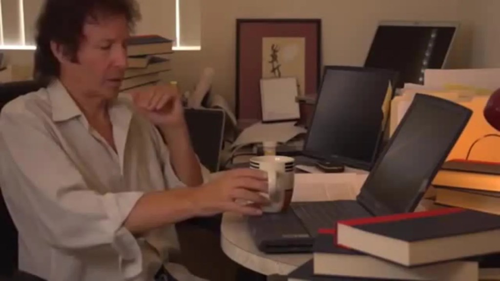 Neil Breen, a writer and hacker with five laptops, places his coffee cop on one of them.